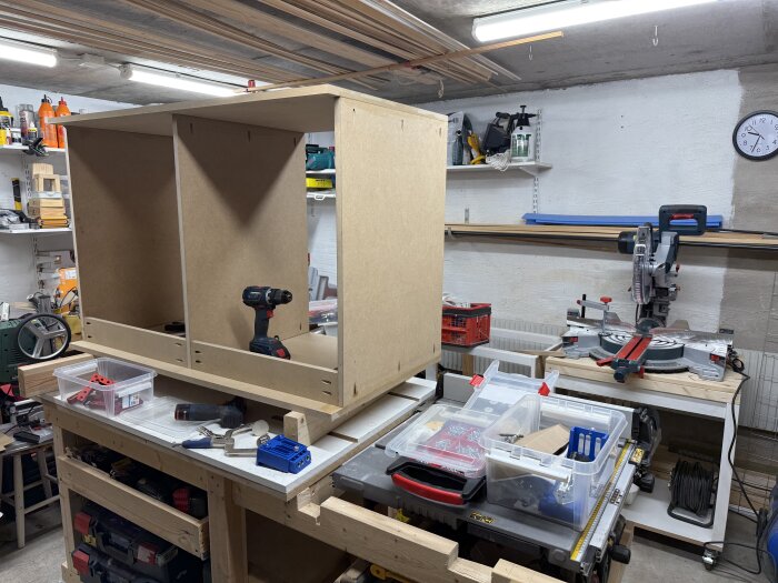 Byggprojekt av en bänk/skåp i en verkstad med olika verktyg och material på bänken.
