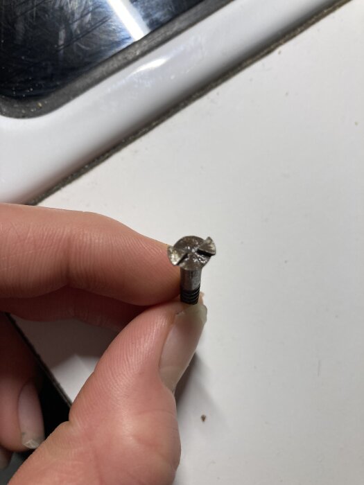 En person håller i en skruv med en annorlunda skruvskalle jämfört med en tidigare modell.