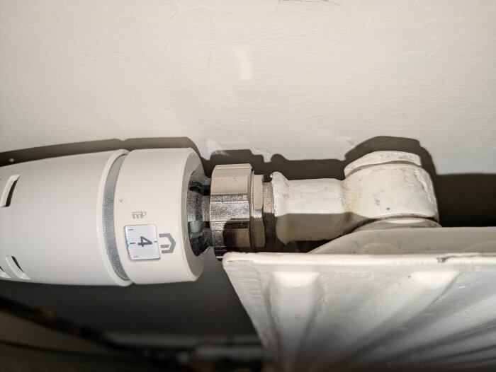 Termostatventil på radiator med inställd temperatur på 4, anslutet till ett rörsystem för uppvärmning i hus från 1927.