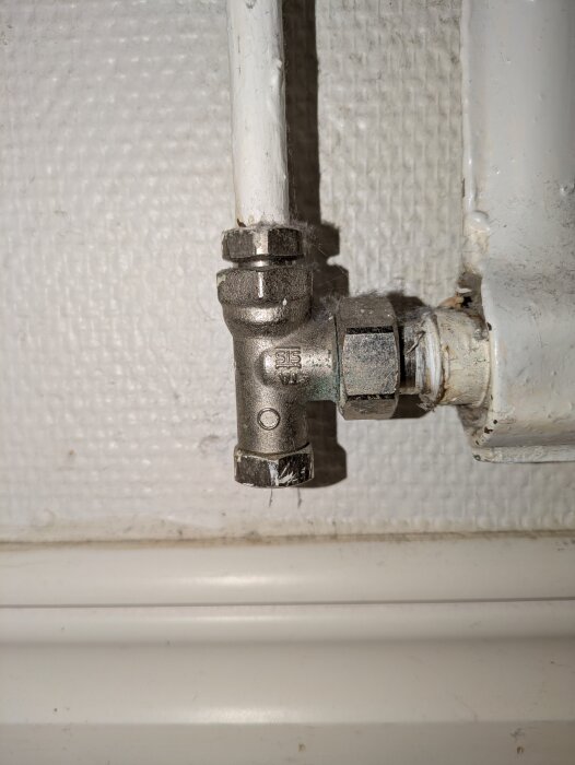 Ventil på radiator med märkningen "SIS"; möjlig justeringspunkt för värmerör.