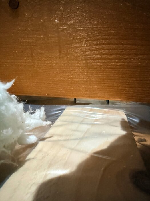 Isoleringsmaterial och träreglar i ett frilagt bjälklag i samband med renovering.