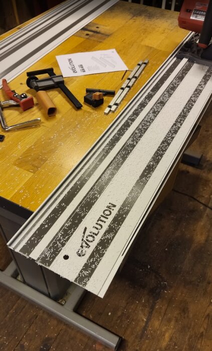 Saw tracks on a workbench with woodworking tools and white plastic shavings scattered around.