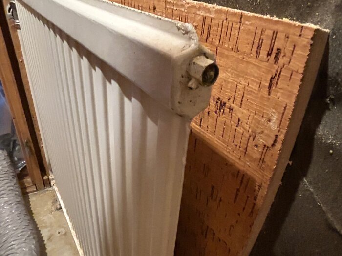 Väggmonterat vitt radiator mot en träpanel, del av renoveringsprojekt.