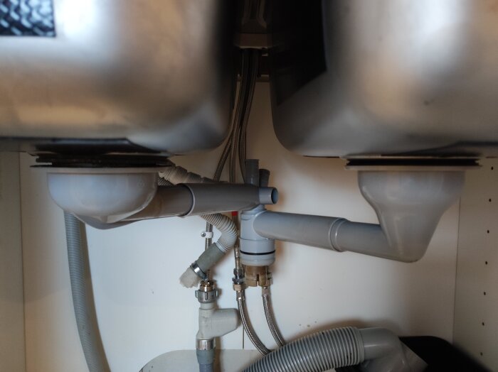 VVS-installation under diskho med grå rör och vattenlås, inte IKEA.