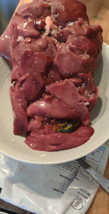 Tallrik med kycklinglever med oönskade delar, ovanpå en förpackning från Axfood.
