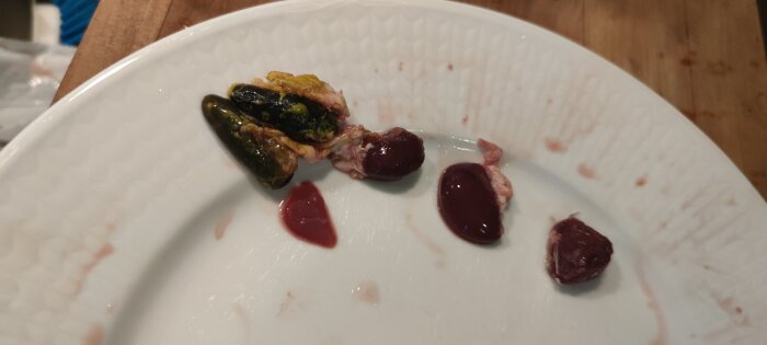 En tallrik med flera små köttdelar, vissa ser ut som kycklinglever och andra som oönskade bitar, delvis täckta av sås eller blod.