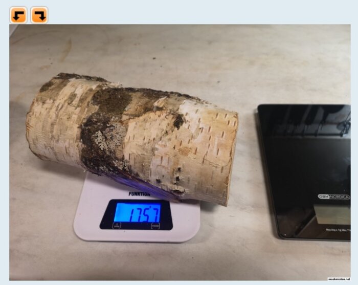 En rå björkkubbe på en köksvåg visar vikten 1.757 kg efter ett års torkning inomhus.