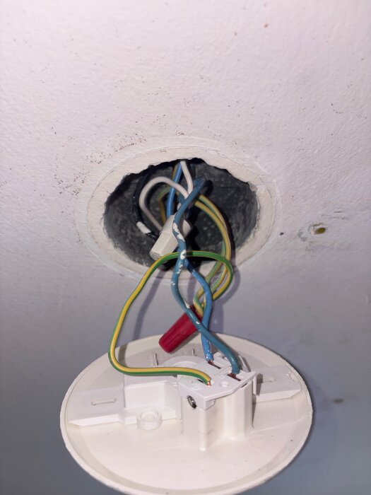 Elektriska kablar och kopplingar kommer ut från taket i ett belysningsprojekt.
