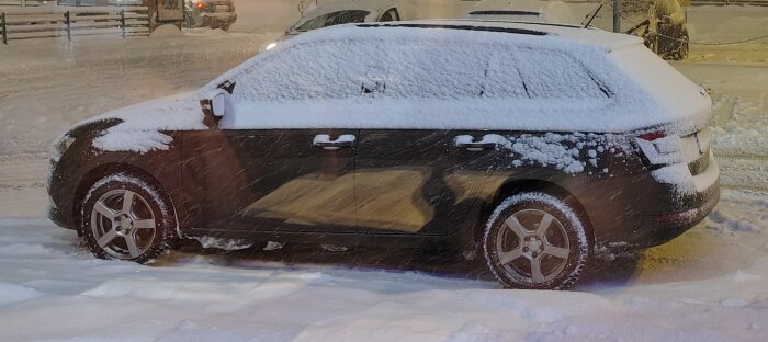 Bil täckt med snö parkerad på vinterväg, snöande väder.