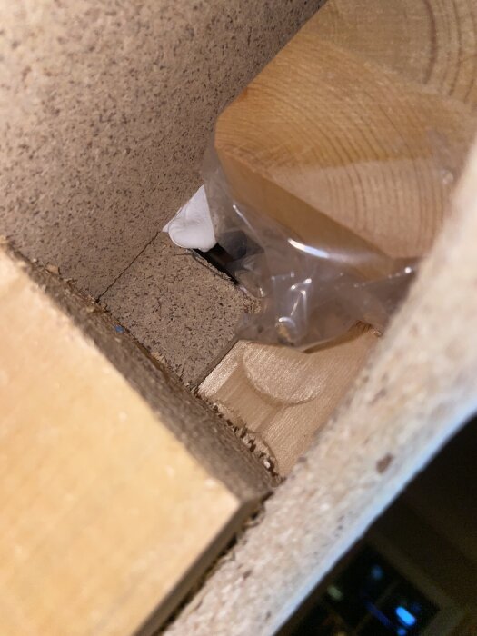 Puurretty reikä kipsiseinässä paljastaa puurunko ja muovikääre sisäpuolella.