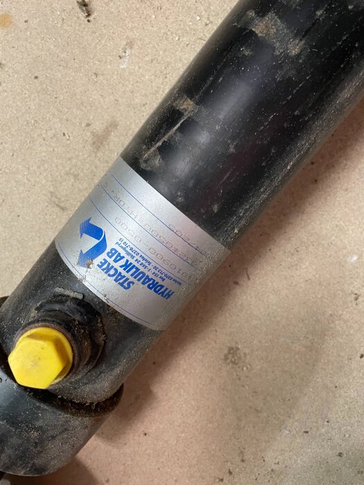 Hydraulcylinder från Starke Hydraulik AB på betonggolv, med gul ventil och etikett synlig.