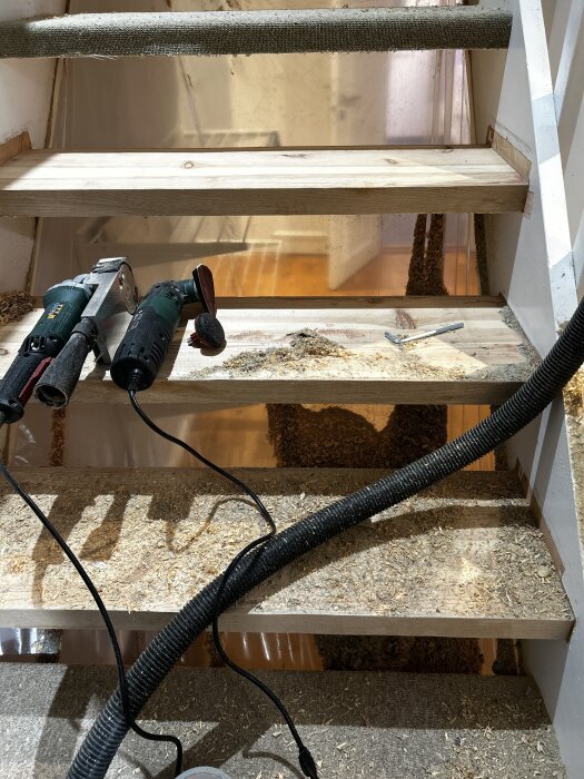 Verktyg och smutsiga trappsteg under renovering, matta borttagen från steg.