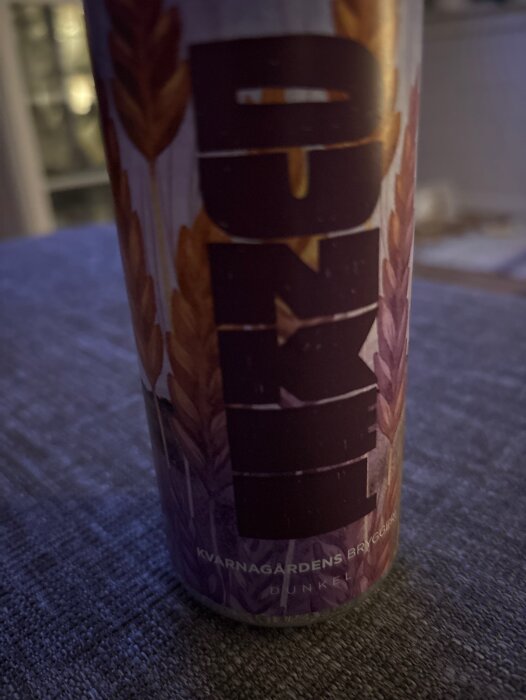 En burk med etiketten "Dunkel" från Kvarnagårdens bryggeri, visas stående på ett bord med dämpad belysning.