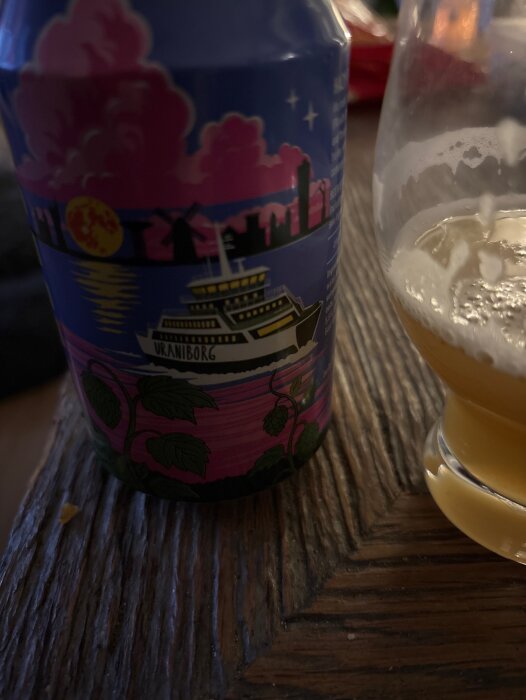En burk med Hazy IPA från Finn, bredvid ett halvfullt glas öl på ett träbord.