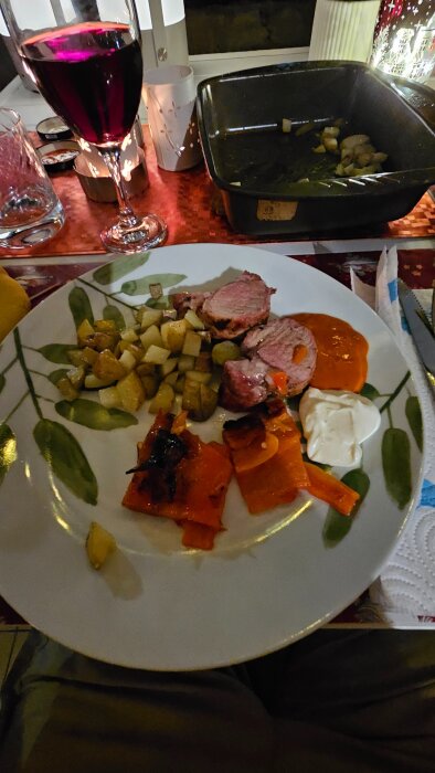 Tallrik med helgrillad Iberico-fläskfilé, ugnsstekta potatisar, grillad röd paprika, mojo rojo och alioli, samt ett glas rödvin.