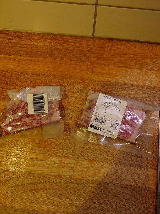 Förpackningar med wagyu ryggbiff på en träbordsyta, etikett från Maxi med pris och vikt synlig.