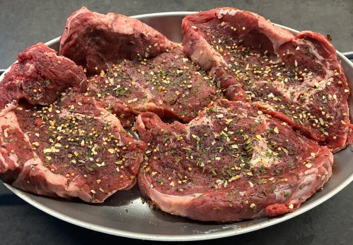 Entrecote-kotletter med kryddor på ett fat, redo för att brynas i stekpannan.