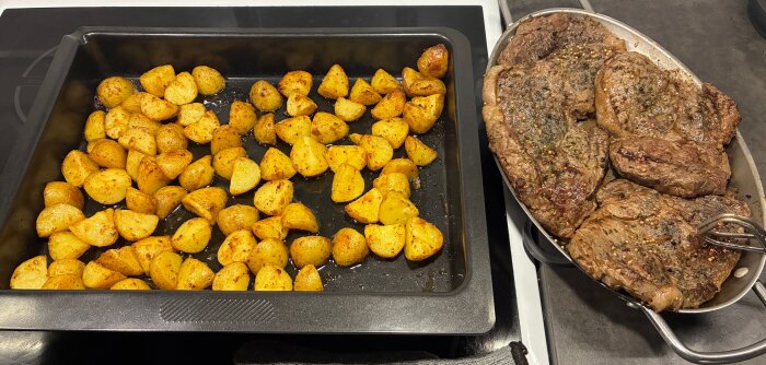 Stekt entrecôte och kryddiga potatisbitar på plåt och metallfat, klart att serveras.