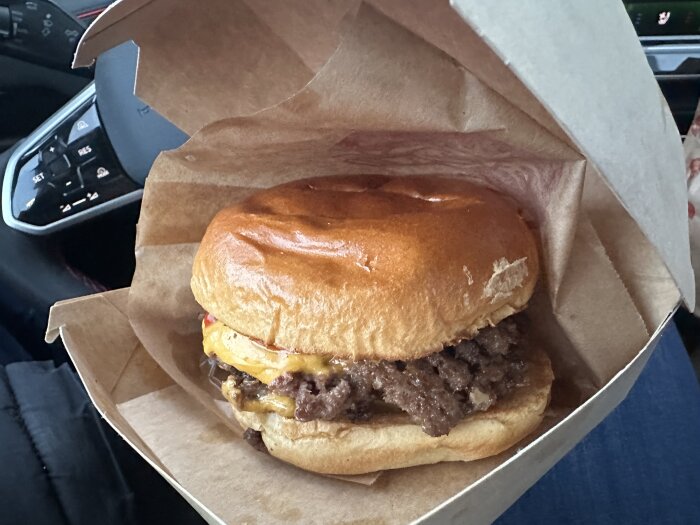 Hamburgare från Mister York med bröd och kött, inslagen i pappersförpackning, fotad i bilen under ett kyligt väder.