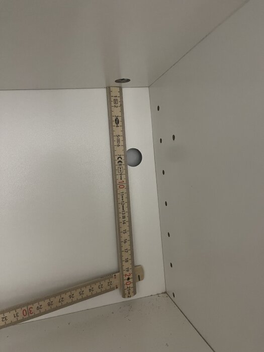 Tumstock mäter inre dimensioner på vit möbel, visar cirka 20 mm tjock stomme.