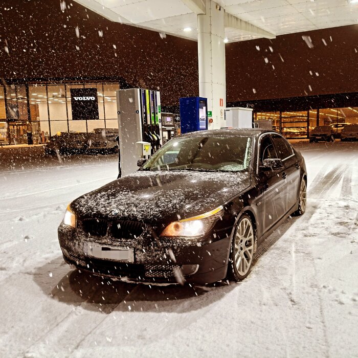 Sänkt E60 BMW med 19" fälgar under ett snöfall på en bensinstation.