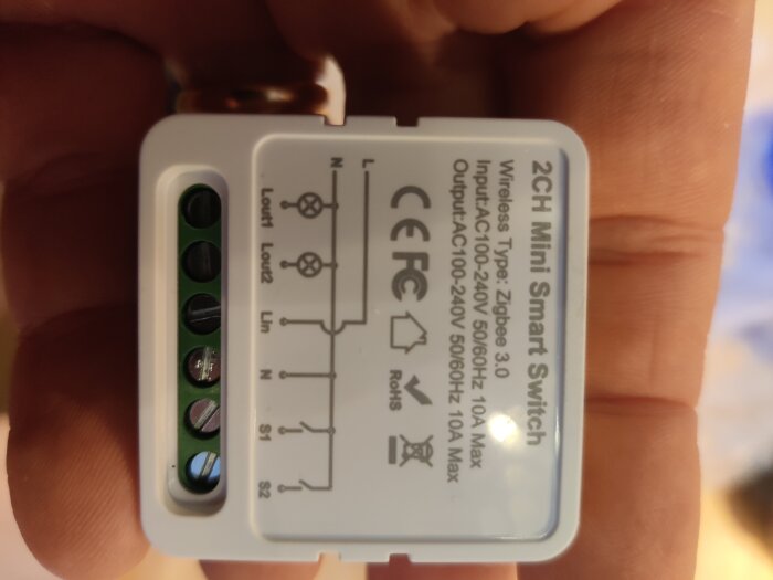 Närbild av en 2-kanals mini smart switch box markerad med trådanslutningar och specifikationer för in- och utgång, med CE- och FCC-märkning.
