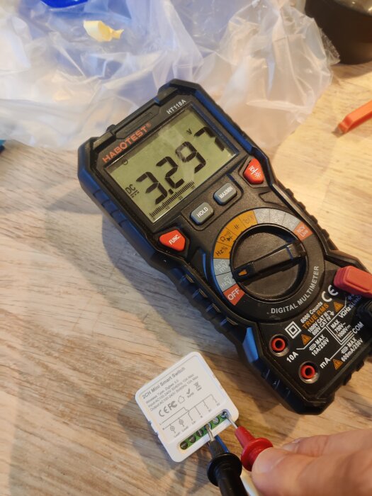 Digital multimeter visar 3,297V, mäter en smart switch med CE-märkning.