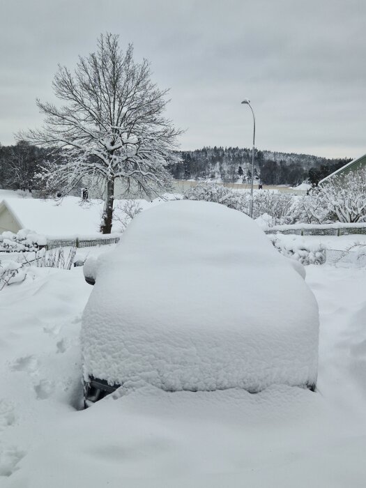 Bil täckt av tjockt lager snö i ett vinterlandskap.
