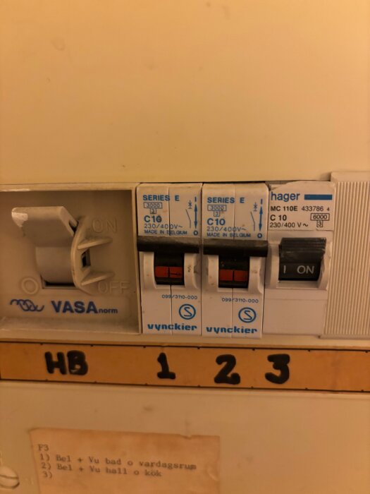 Bild på ett säkringsskåp med tre automatsäkringar och en huvudbrytare märkt "VASA", med handskriven märkning "HB 1 2 3".