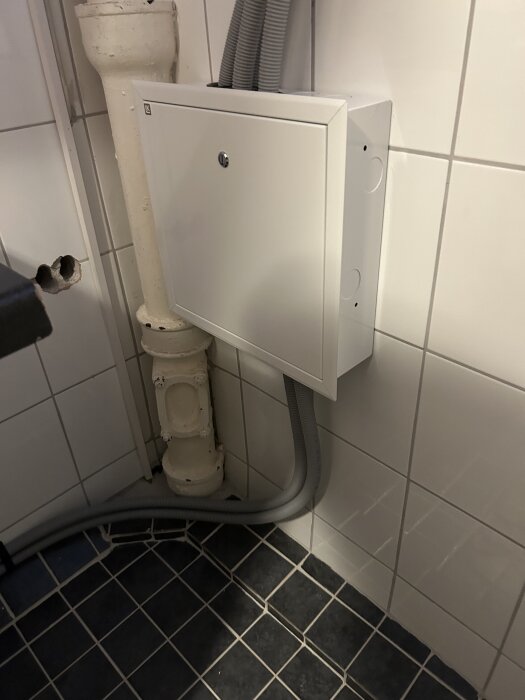 Rörsystem i tvättstuga med ny rördragning. Ett kopplingsskåp på kaklad vägg, flexibla rör ansluts från taket till diskbänk.