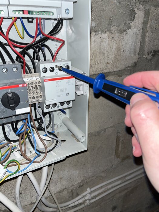 Person testar spänning i elcentral med en multimeter.