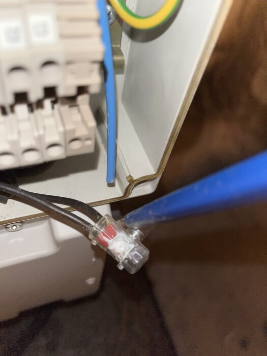 Elkabeldragning i en elcentral med färgkodade kablar, anslutna via kopplingsplintar och en blå isolerad kabel som leder från förgrening.