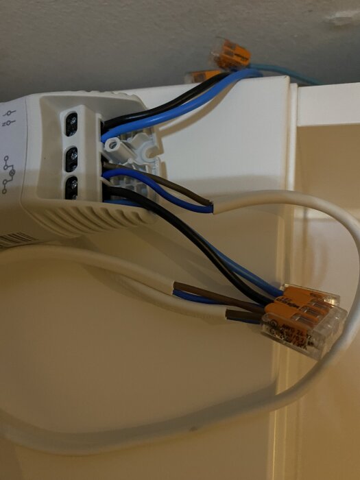 Elektrisk transformator med flera ledningar anslutna, varav några är blå och bruna. Trådförbindelse synlig med plintar.