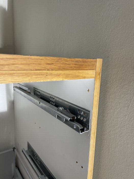 Köksskåp med metallisk lådskena på insidan, frågar om möjlighet att uppdatera med soft close-funktion.