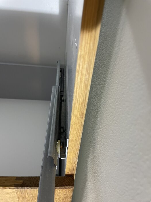 Närbild av skenor på en kökslåda i ett äldre Kvänum-kök, med fokus på lådans struktur och kant.