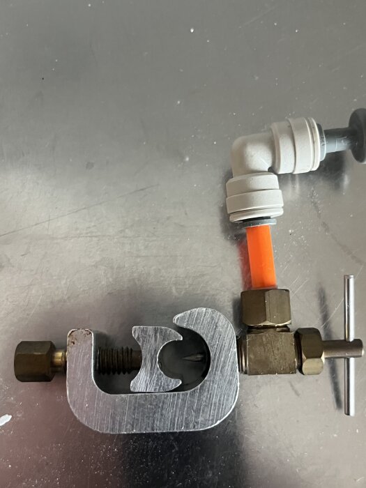 Metallisk komponent fäst på ett vattenrör, misstänkt för att vara en övertrycksventil.