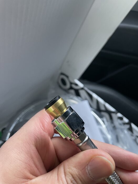 Närbild av en hand som håller en flexslang med en koppling, del av installation för en köksblandare FM Mattsson 9000E.
