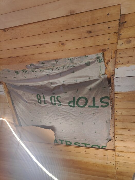 Närbild på tak där ångbroms är installerad under takpanel; delar av ångbromsen är lösa och synlig mellan takstolar.