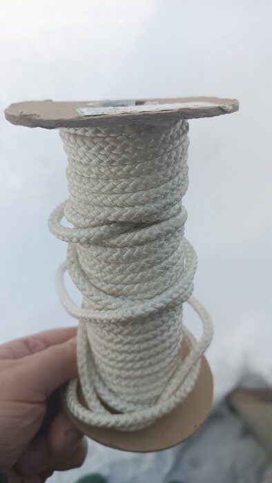 Rulle med vit flätad rep som hålls i handen.