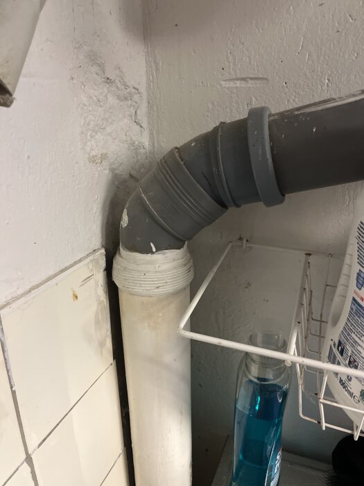 Överdimensionerat rör i kök med synligt vitt och grått avloppsrör anslutet vid väggen.
