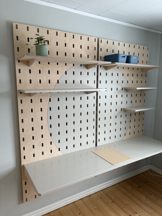 Verkstadsliknande pegboardvägg med hyllor, skrivbord i björkplywood och målad MDF.