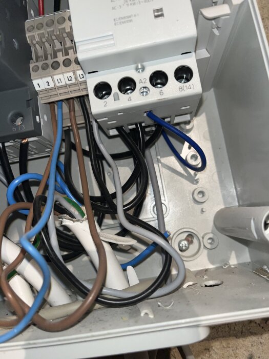 Elektrisk kopplingsbox med olika färgade kablar, inklusive en blå kabel som går till anslutning märkt "N".