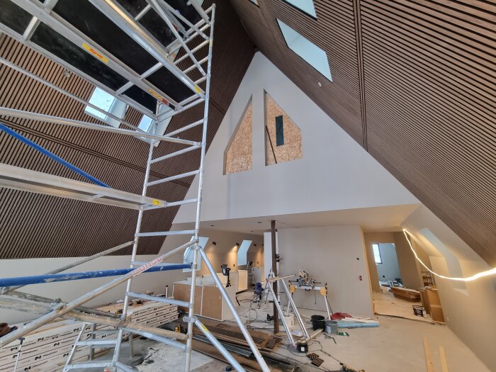 Byggarbetsplats i kök med ställning, montering av skåp pågår, träpaneler förbereds för vägg och takinstallation.