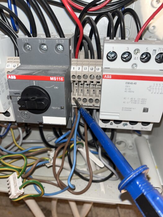 Stoppensats visar en elektrisk kopplingsbox där en brun kabel pekas ut med en skruvmejsel.