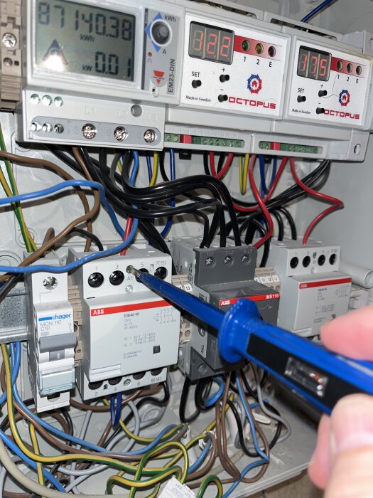 Elektrisk kopplingsbox med mätinstrument som kontrollerar ström, där ledningar och mätare syns tydligt.