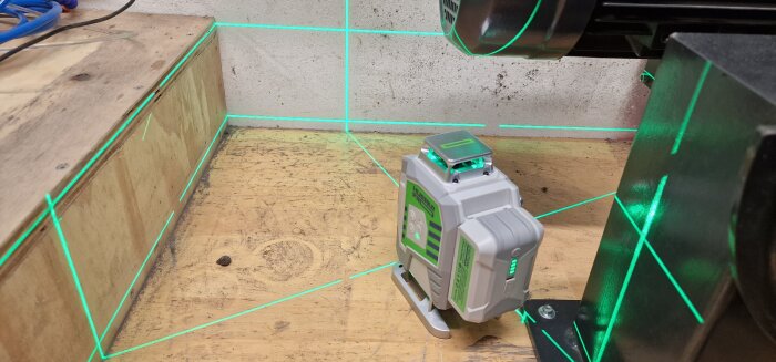 Laserverktyg projicerar gröna linjer på en arbetshörna för precision vid byggprojekt.