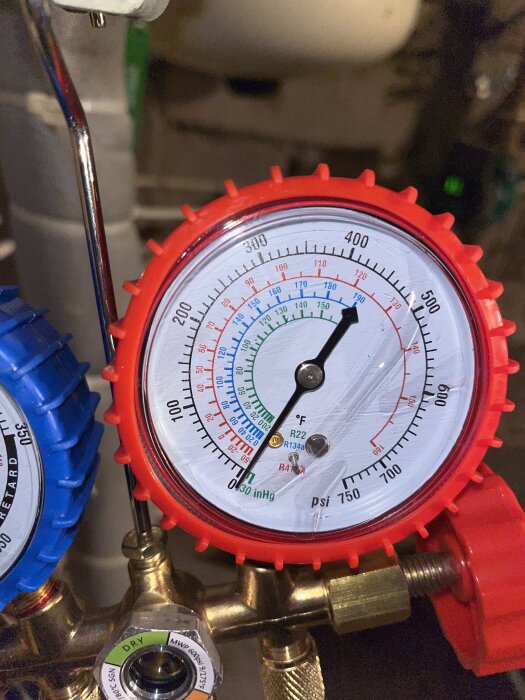 Tryckmätare med röd ram, visar olika skalor i psi och temperatur för kylmedia R22, R134a, R410a. Används för att kontrollera tryck i system.