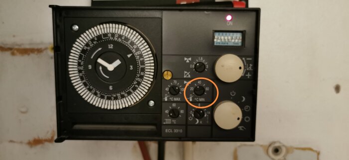 Gammal Danfoss fjärrvärmecentral, modell ECL 3310, med inställningsratt markerad för justering av temperatur.