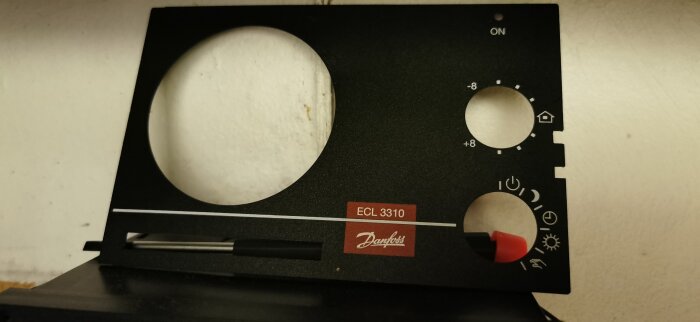 Kontrollpanel på en Danfoss ECL 3310 fjärrvärmecentral, med flera valbara inställningar och en röd knapp.