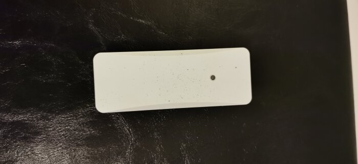 Vit rektangulär enhet mot svart bakgrund, identifierad som en utomhusgivare.